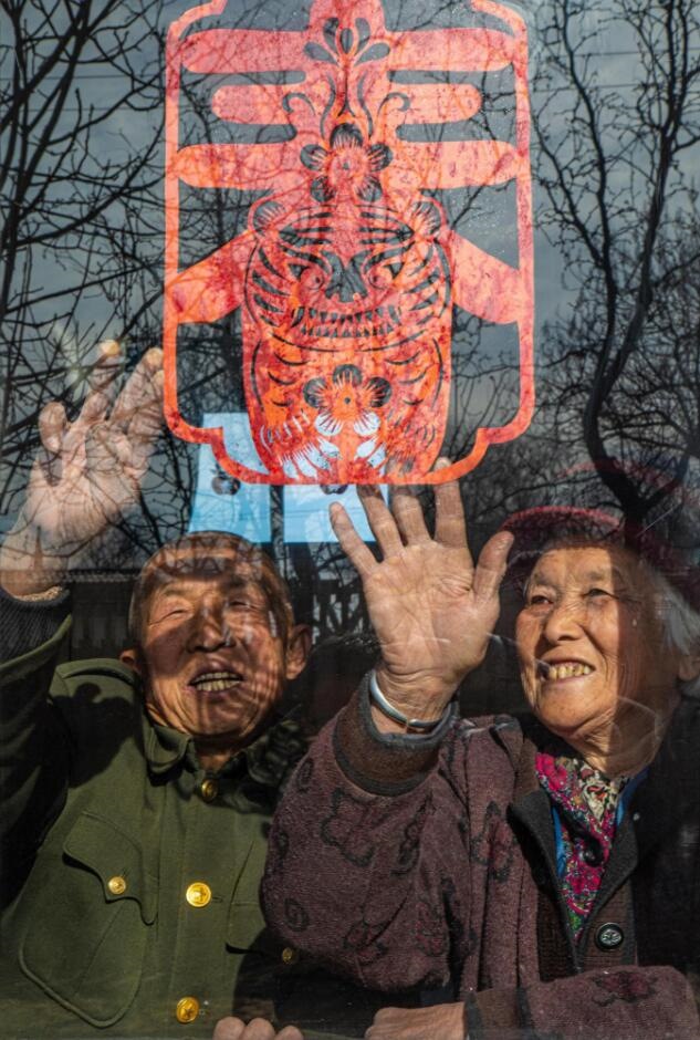 臘月里，霍州市師莊鄉(xiāng)馮南垣村村民師榮光(左)在災后重建的新家里貼窗花。(霍州市委宣傳部供圖)