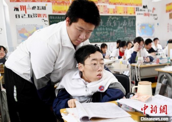 朱金祥(左)把鐘華強(qiáng)放到課堂座位上后，都要把他擺正好，確認(rèn)安全后才回到自己的座位上。 卓忠偉 攝