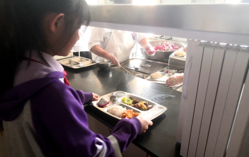 伊金霍洛旗第一小學(xué)學(xué)生正在打飯，今天的飯菜是三菜一湯外加水果，學(xué)生可以多次盛取，吃飽為止。人民網(wǎng)記者 孫博洋攝