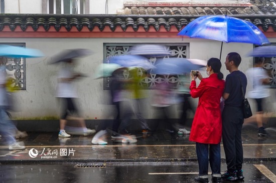 6月7日，在浙江省2023年普通高校招生考試鎮(zhèn)海中學考點，家長冒雨目送子女進入考場。人民網(wǎng) 章勇濤攝