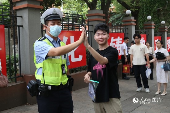 6月7日8時許，武漢中學考點門口，交警在維護秩序，并?？忌鸢耦}名。人民網(wǎng)記者 肖璐欣攝