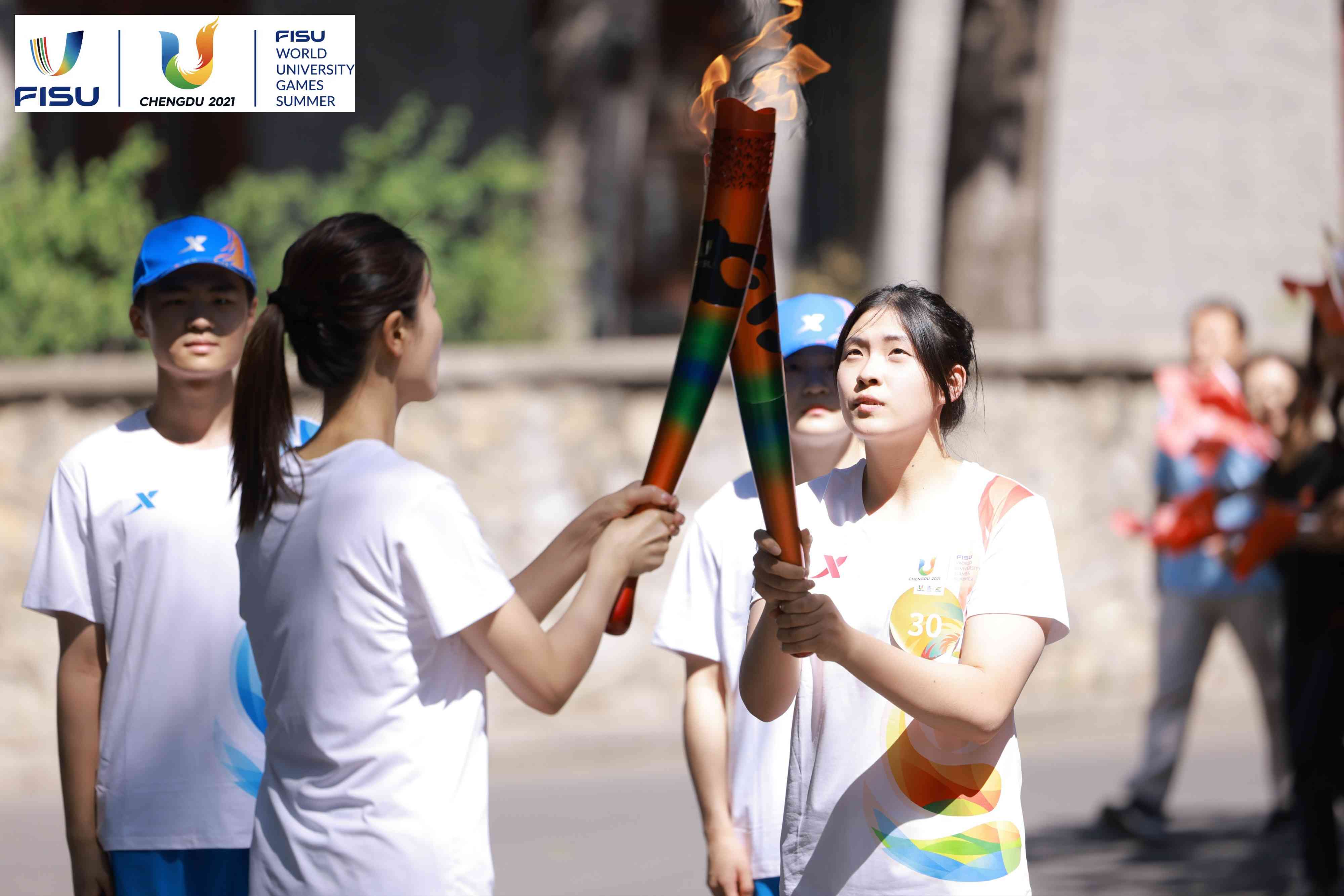 兩名大運會火炬手進行火炬?zhèn)鬟f。 圖片來源：成都大運會執(zhí)委會供圖
