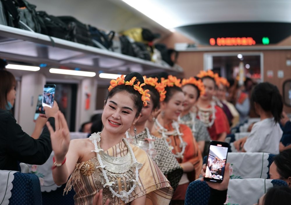 2023年4月13日，老撾工作人員在D887次國(guó)際旅客列車上表演。當(dāng)日，中老鐵路從中國(guó)昆明南站、老撾萬(wàn)象站雙向?qū)﹂_(kāi)D887次和D888次國(guó)際旅客列車，兩地乘火車可當(dāng)日通達(dá)。中老鐵路是高質(zhì)量共建“一帶一路”的標(biāo)志性工程。新華社記者 邢廣利 攝