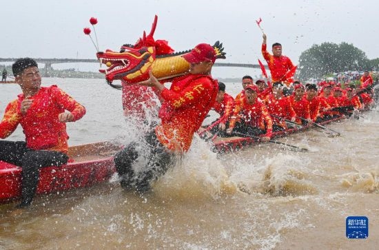6月22日，在湖南省岳陽市湘陰縣湘江臨資口水域，參加龍舟賽的隊(duì)員接“龍頭”下水。