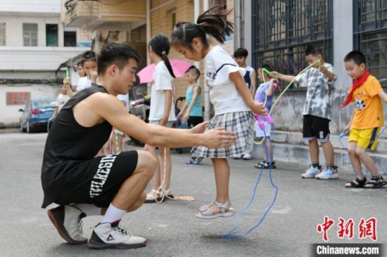圖為大學(xué)生志愿者在教孩子們學(xué)跳繩。廖光福 攝