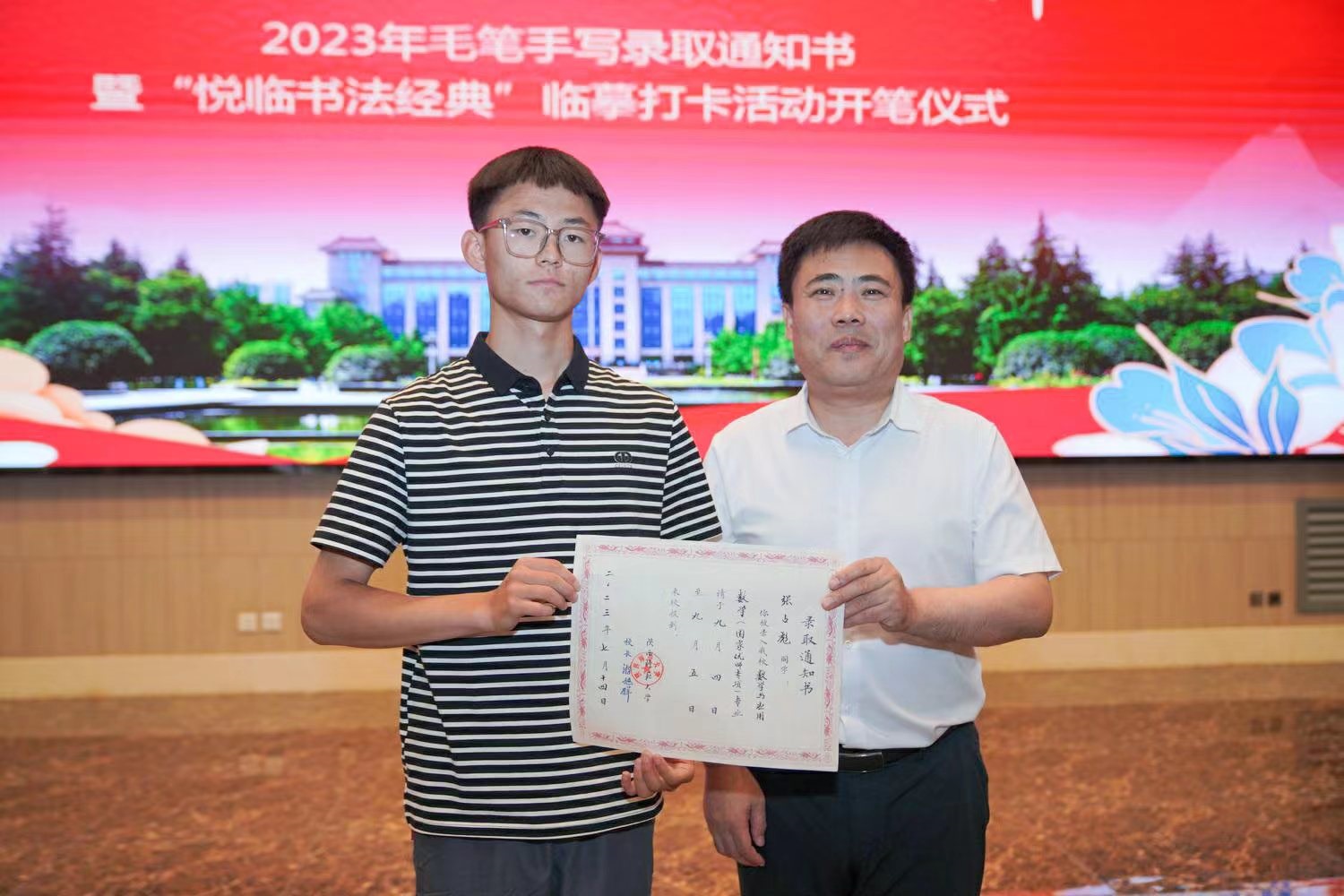 陜西師范大學黨委書記李忠軍為2023級新生代表張占彪同學發(fā)放錄取通知書。校方供圖