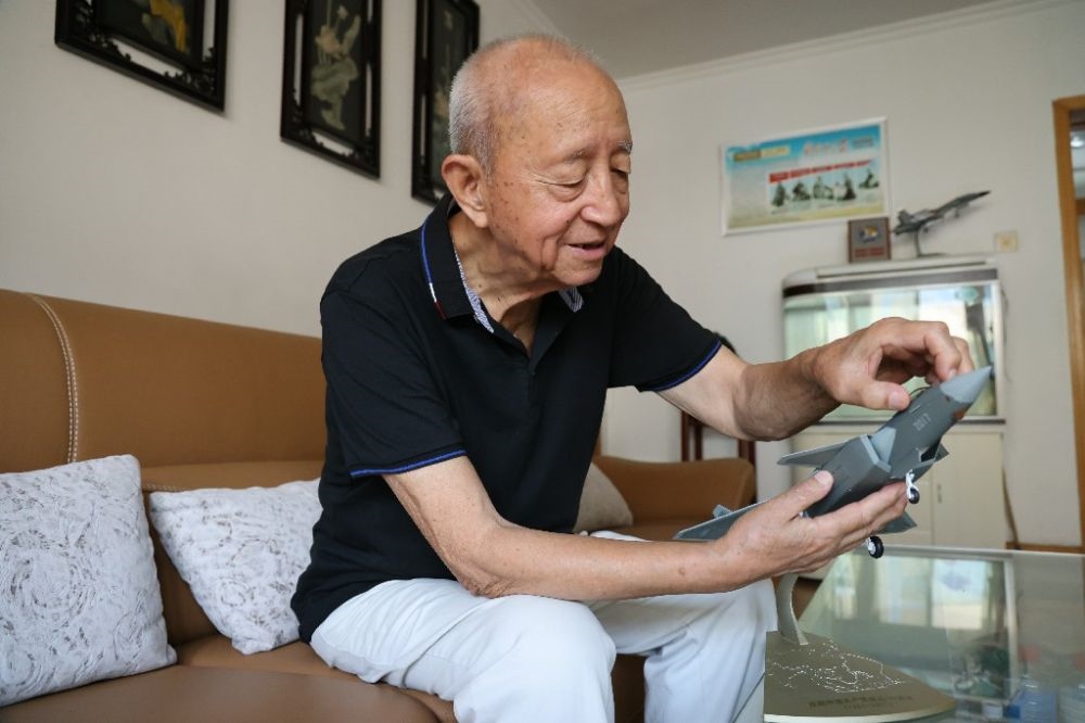 ↑2023年7月24日，新中國第一代飛行員陶偉在家中擦拭殲-20飛機(jī)模型。新華社發(fā)（張瑞 攝）