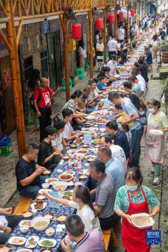 7月29日，在重慶市綦江區(qū)安穩(wěn)鎮(zhèn)，人們?cè)凇懊缂曳蚬?jié)”上吃長(zhǎng)桌宴。新華社記者 唐奕 攝