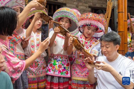 7月29日，在重慶市綦江區(qū)安穩(wěn)鎮(zhèn)，當(dāng)?shù)鼐用裨凇懊缂曳蚬?jié)”上用傳統(tǒng)習(xí)俗向游客表達(dá)祝福。新華社記者 唐奕 攝