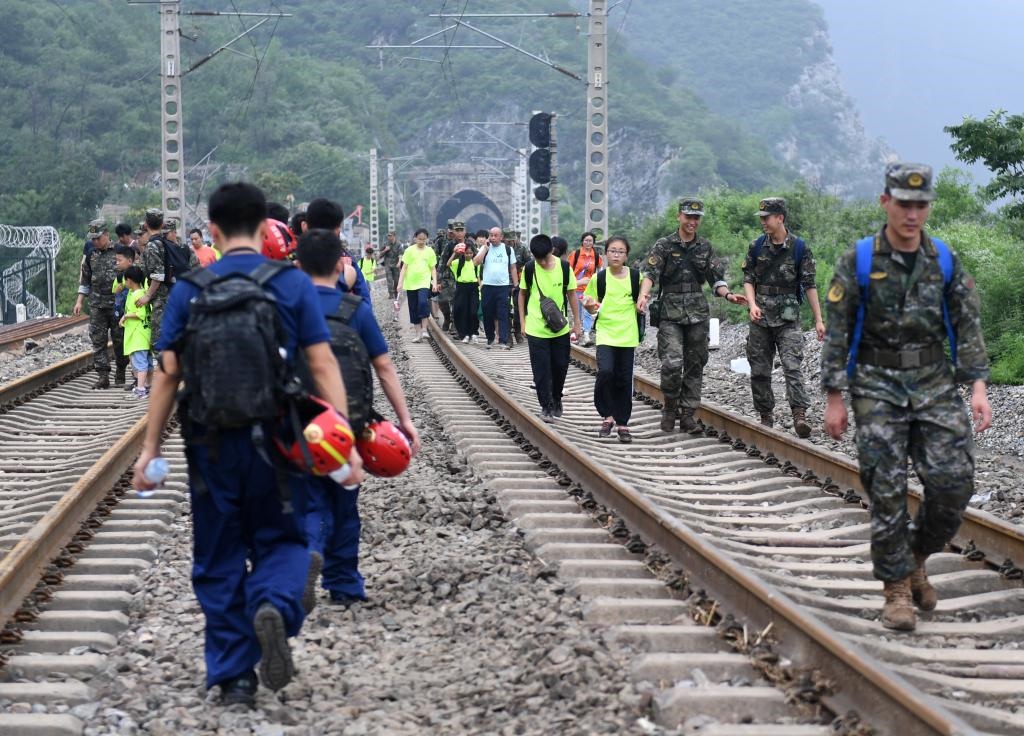 8月2日，部分滯留在北京市門(mén)頭溝山區(qū)受困列車(chē)的旅客，在救援人員幫助下前往轉(zhuǎn)運(yùn)客車(chē)。新華社記者張晨霖 攝