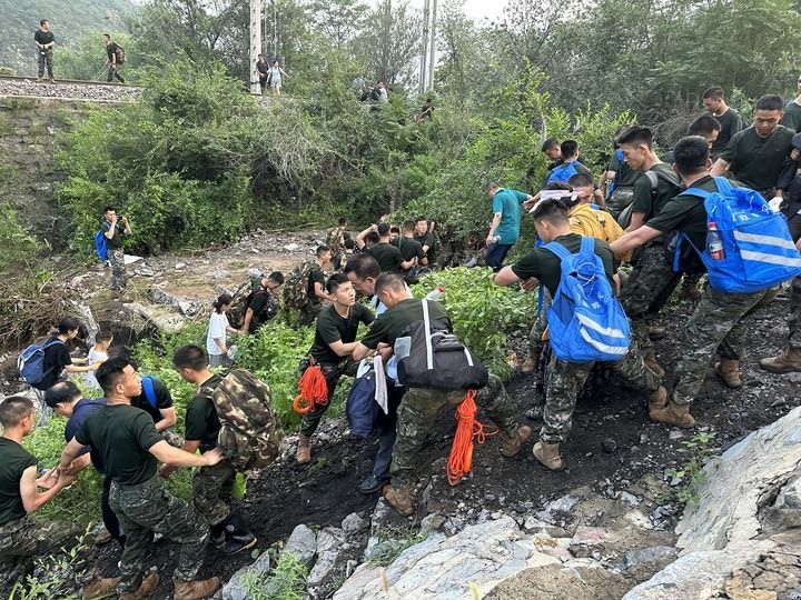 8月2日，Z180次受困列車的旅客在武警北京總隊機動第三支隊官兵的幫助下徒步前往轉(zhuǎn)運客車（手機照片）。新華社記者 王艷剛 攝