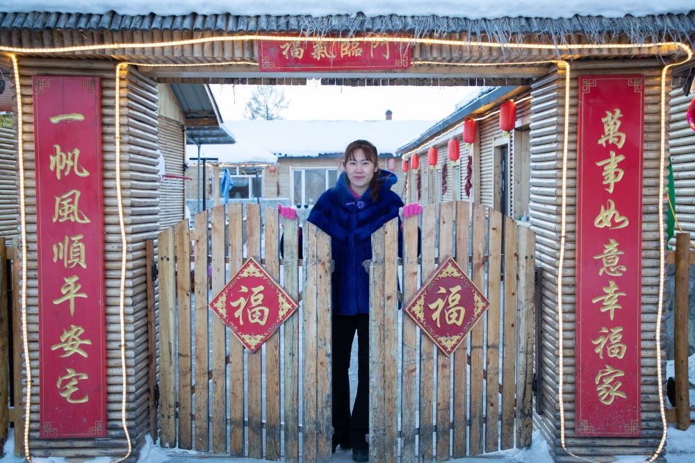 北極村民宿經(jīng)營(yíng)者史瑞娟在門(mén)前迎候入住的游客（2023年1月7日攝）。