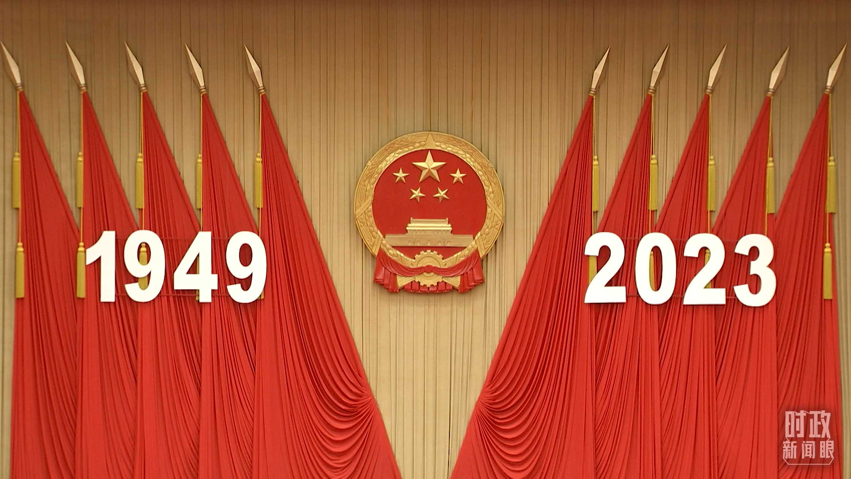 △人民大會堂宴會廳內(nèi)，主席臺上方高懸著莊嚴的國徽，“1949－2023”大字年號在鮮艷的紅旗映襯下格外醒目。