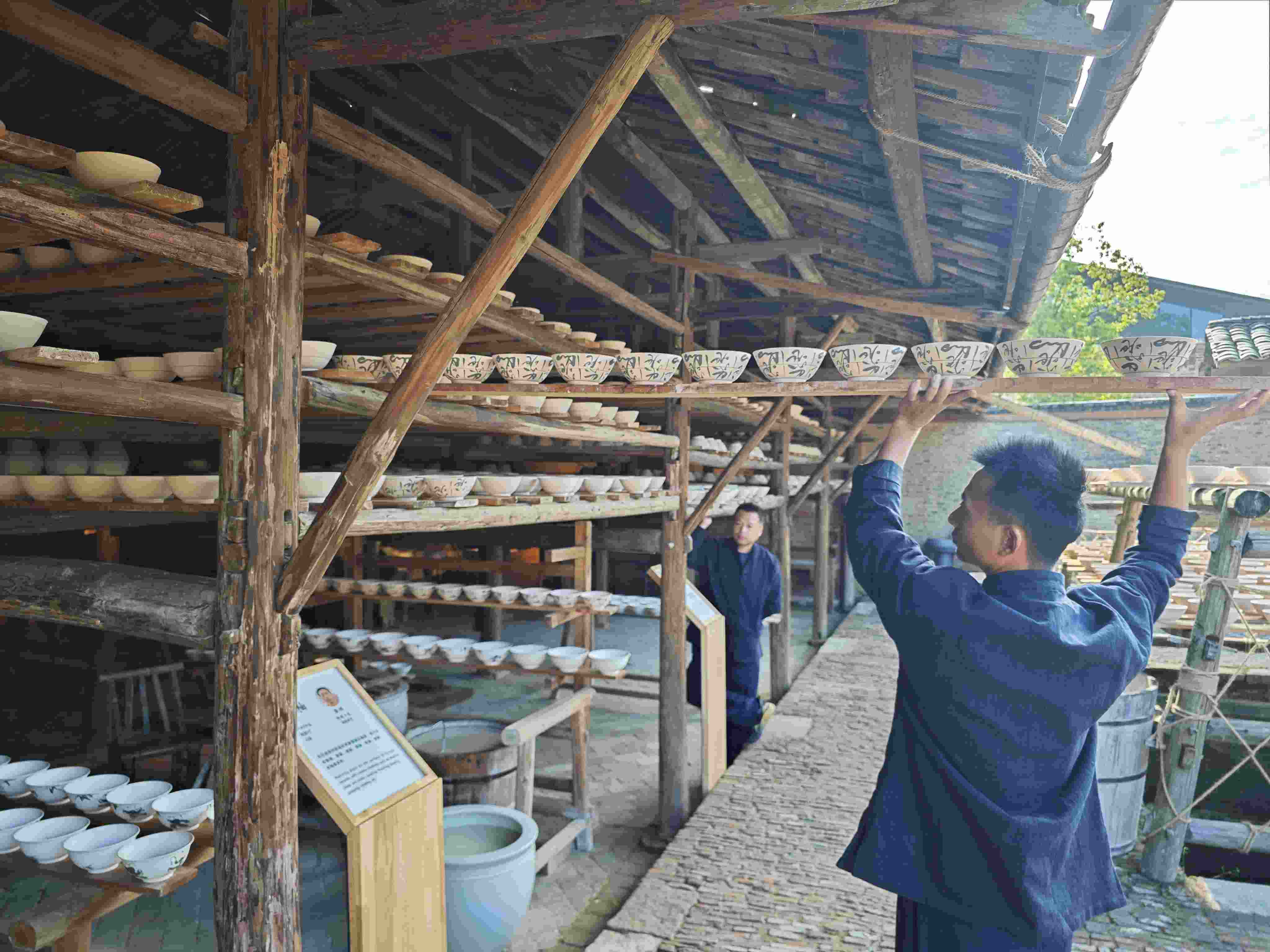 △陶陽里歷史文化街區(qū)里，工匠將陶瓷工藝品放到架上晾干。（總臺央視記者彭漢明拍攝）