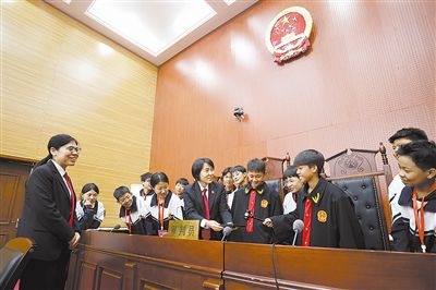 圖③：同學(xué)們穿法袍、敲法槌，爭做“小法官”。
