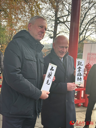 柏林市長韋格納（右）、動(dòng)物園監(jiān)事會(huì)主席布魯克曼（左）手持中國文化中心工作人員現(xiàn)場手書的中文名字。人民網(wǎng)記者 徐馨攝