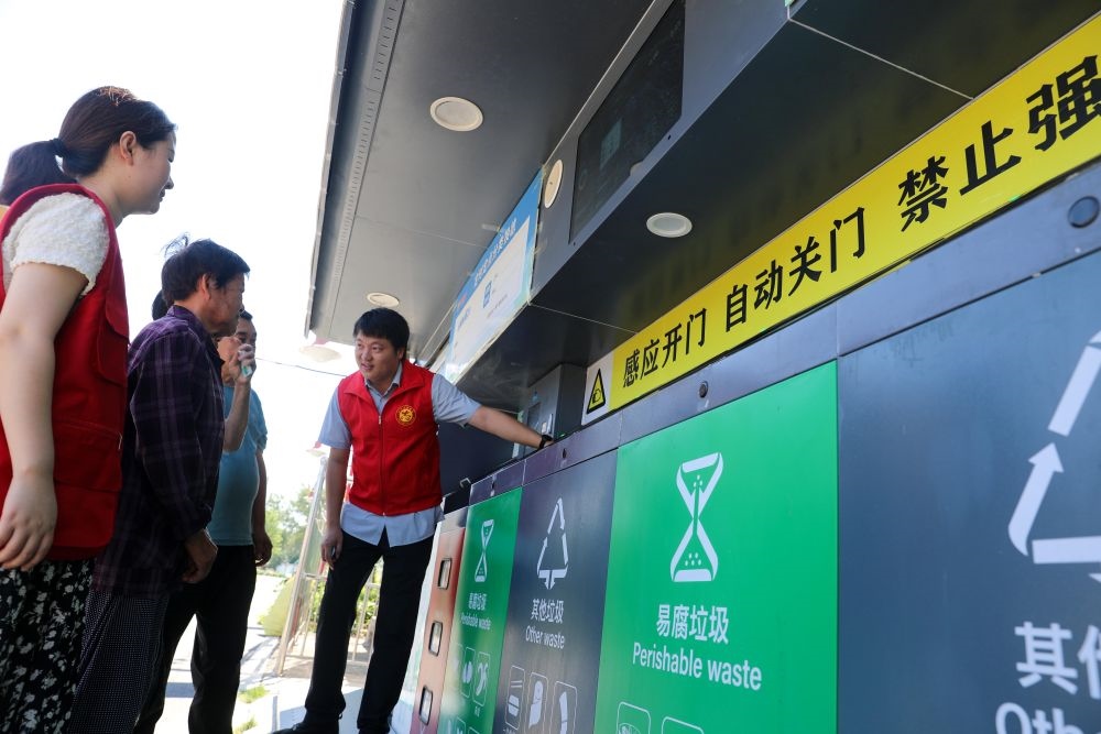 在安徽省合肥市長豐縣莊墓鎮(zhèn)棗林社區(qū)，志愿者指導(dǎo)居民使用智能垃圾分類回收設(shè)備（2023年9月1日攝）。新華社記者 曹力 攝