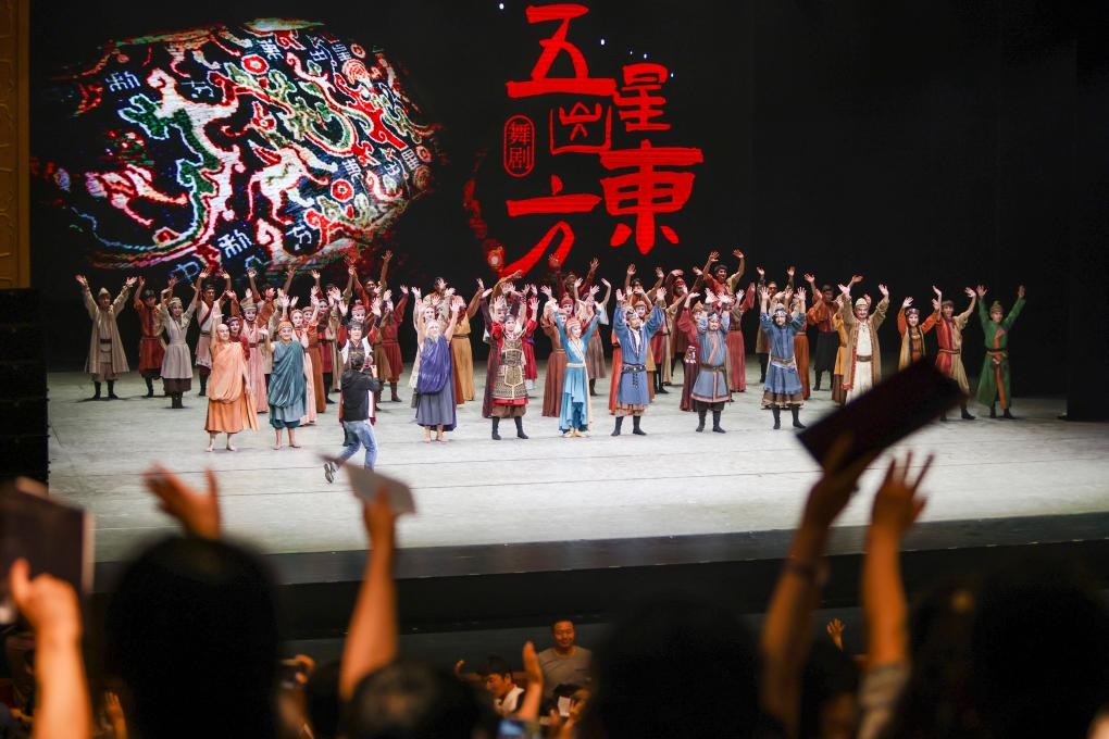 2023年7月31日，新疆和田地區(qū)新玉歌舞團(tuán)在烏魯木齊京劇院演出舞劇《五星出東方》后和觀眾互相揮手致意。這場(chǎng)演出是第六屆中國(guó)新疆國(guó)際民族舞蹈節(jié)的參演劇目之一，曾榮獲國(guó)家“文華獎(jiǎng)”等。新華社記者 郝昭 攝