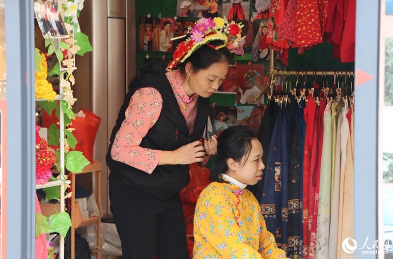 泉州府文廟附近，一名店主正為過(guò)路游客梳理頭發(fā)以佩戴“簪花圍”。人民網(wǎng) 黃東儀攝