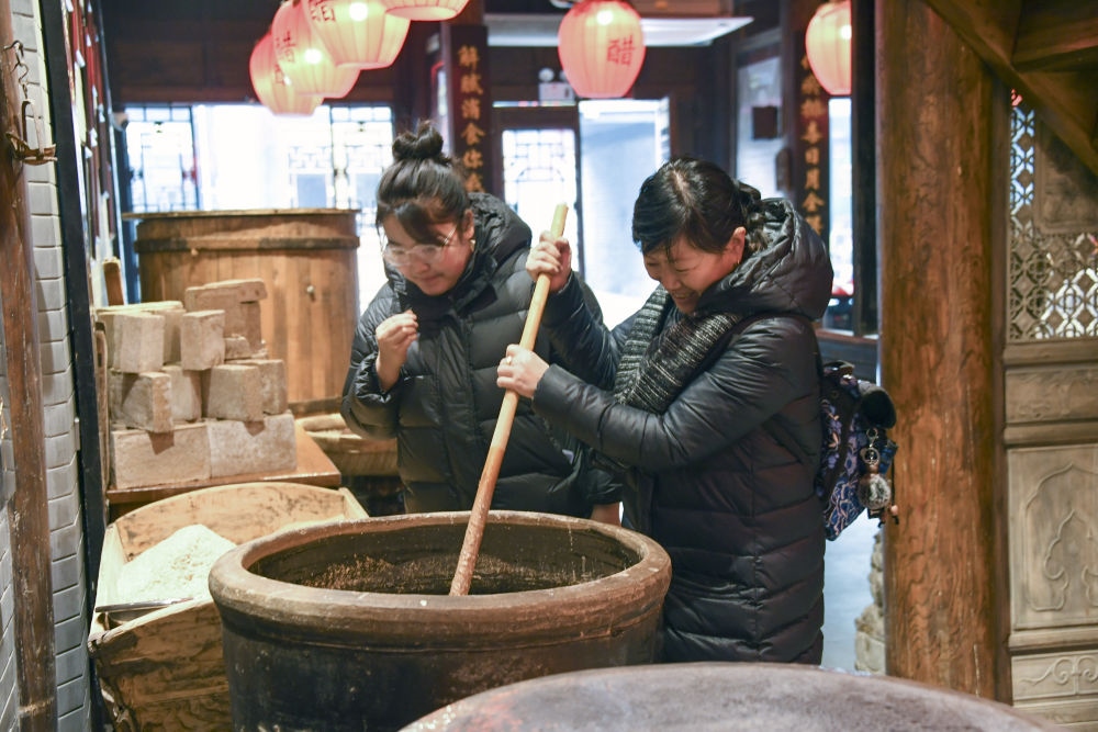 游客在平遙古城東湖老醋坊內(nèi)體驗(yàn)陳醋發(fā)酵打耙（2022年1月28日攝）。新華社發(fā)（梁生仁攝）