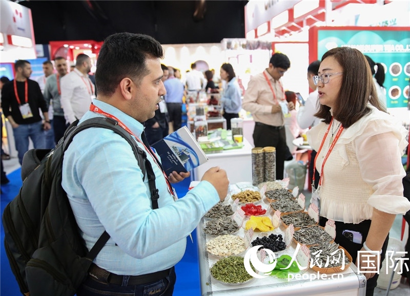 圖為一家中國(guó)干果參展企業(yè)代表與采購(gòu)商洽談。人民網(wǎng) 塔里克·易卜拉欣攝