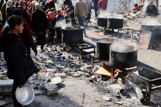  2月27日，在加沙地帶北部的杰巴利耶難民營，人們等待領取食物。新華社發(fā)（穆罕默德·阿里攝）