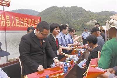 法院干警及相關(guān)部門工作人員對(duì)群眾進(jìn)行生態(tài)環(huán)境保護(hù)普法教育。