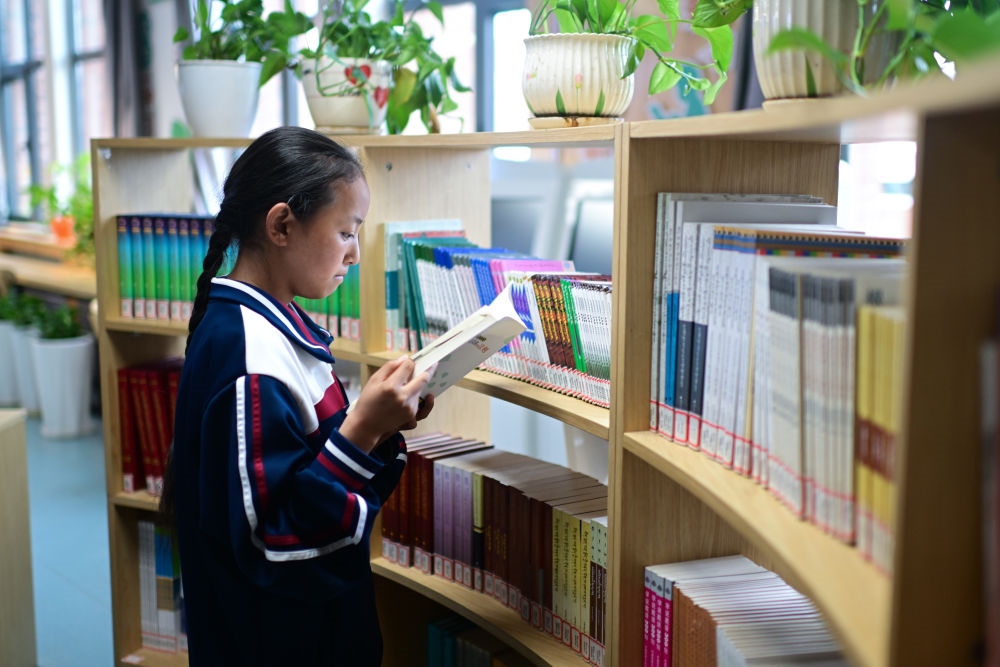 6月18日，果洛西寧民族中學學生尼東拉毛在圖書室看書。