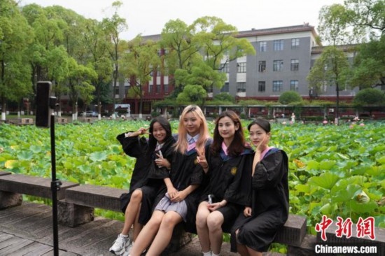 6月19日，時值一年畢業(yè)季，四川大學(xué)望江校區(qū)荷花池里的荷花盛開，成為了畢業(yè)生們的打卡圣地，吸引了眾多畢業(yè)生拍照留念。圖為畢業(yè)生在荷花池邊拍照留念。中新社記者 安源 攝