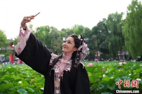 6月19日，時值一年畢業(yè)季，四川大學(xué)望江校區(qū)荷花池里的荷花盛開，成為了畢業(yè)生們的打卡圣地，吸引了眾多畢業(yè)生拍照留念。圖為畢業(yè)生在荷花池邊拍照留念。中新社記者 安源 攝