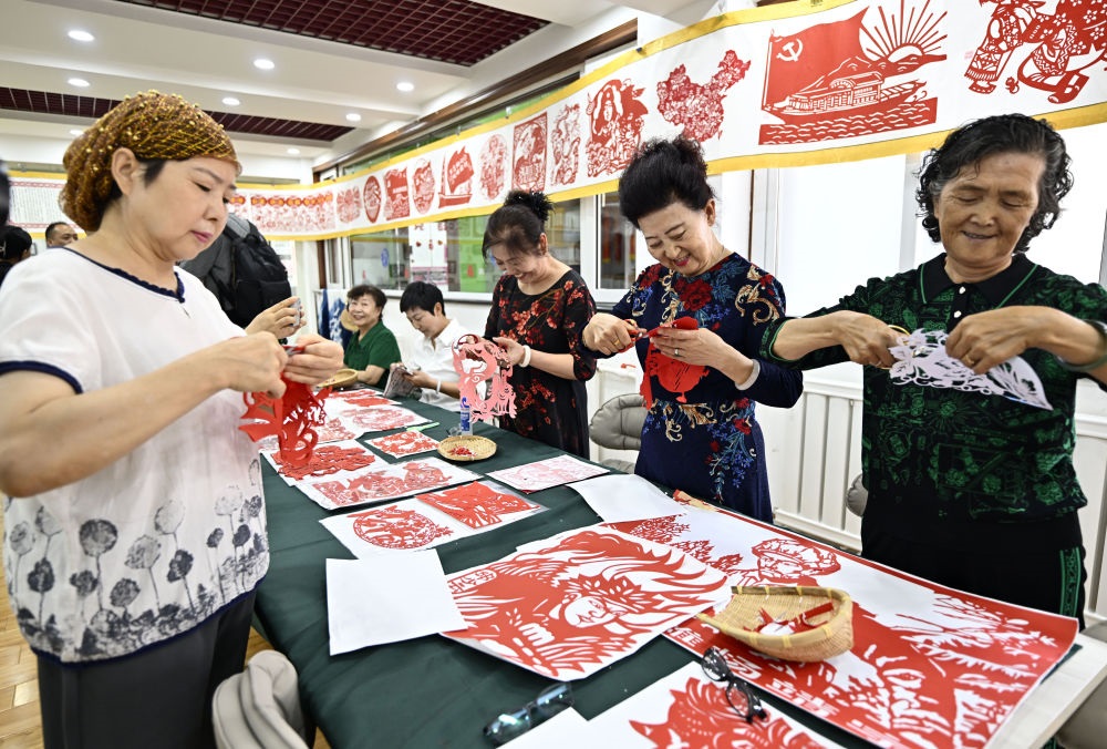 6月19日，長城花園社區(qū)居民在社區(qū)“才藝堂”制作剪紙。