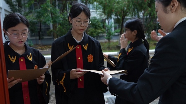 圖①：武平法院干警向學生分發(fā)道具卷宗。