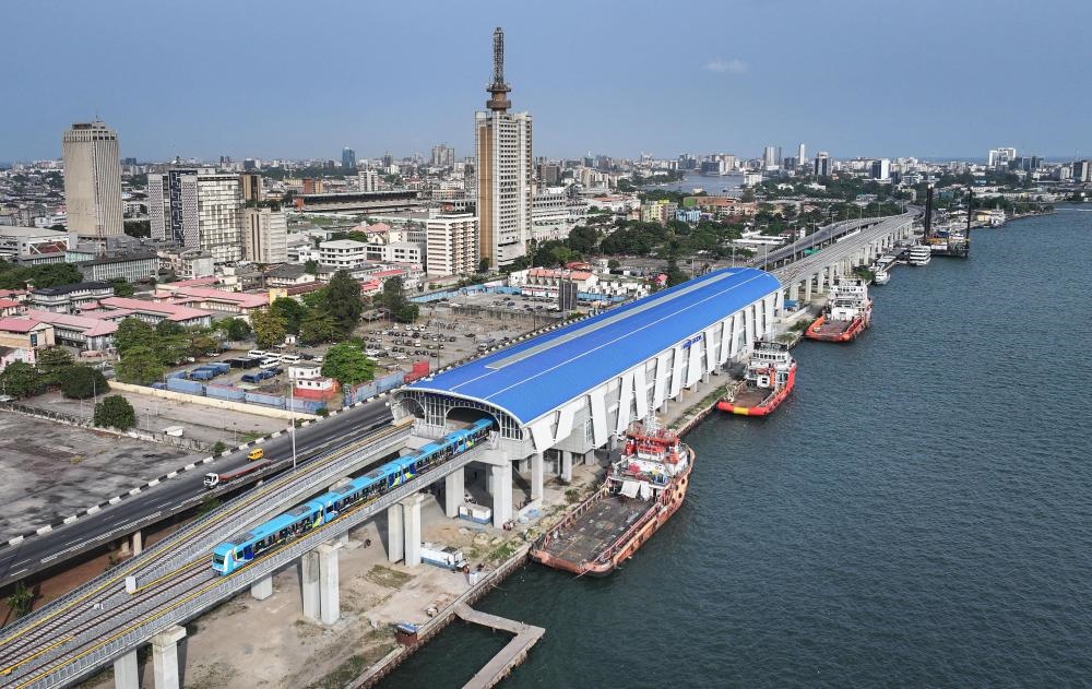 2024年3月2日，在尼日利亞拉各斯，一列輕軌藍線列車駛?cè)氪a頭站（無人機照片）。拉各斯輕軌藍線是西非地區(qū)首條由中國企業(yè)自主設(shè)計、建造、施工、運營的電氣化城市軌道交通項目。新華社記者 韓旭 攝