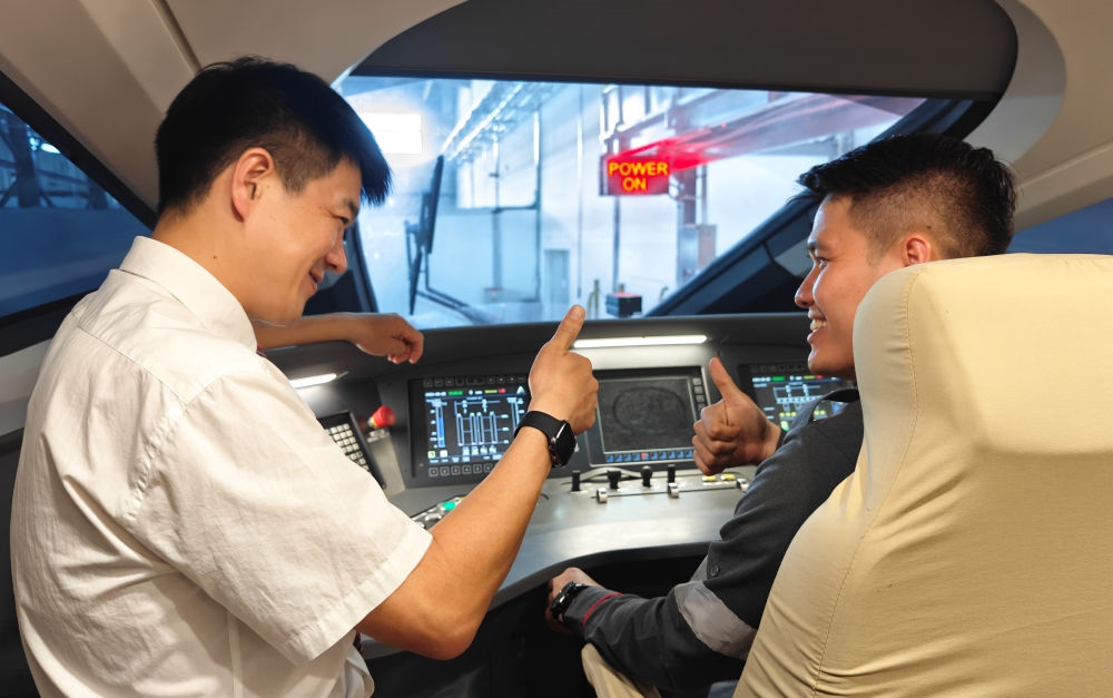 2023年8月25日，在印度尼西亞萬隆的雅萬高鐵德卡魯爾動車所內(nèi)，中國師傅穆振（左）向印尼火車司機塞蒂亞萬講解動車組出庫前的上電作業(yè)。新華社記者 徐欽 攝
