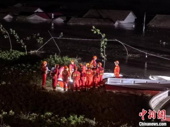  7月6日凌晨3時，在湖南岳陽華容縣團洲垸洞庭湖一線堤防，救援人員剛剛完成一次救援任務(wù)，遠處是被淹的民房。中新社記者 白祖偕 攝