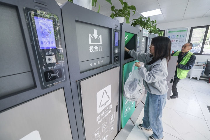 2024年4月10日，在浙江省湖州市吳興區(qū)飛英街道新華府小區(qū)內，居民在垃圾分類智能系統(tǒng)的指導下進行垃圾分類投放，居民的投放情況將實時匯總到智慧服務平臺，會有相應的積分獎勵。新華社記者 徐昱 攝