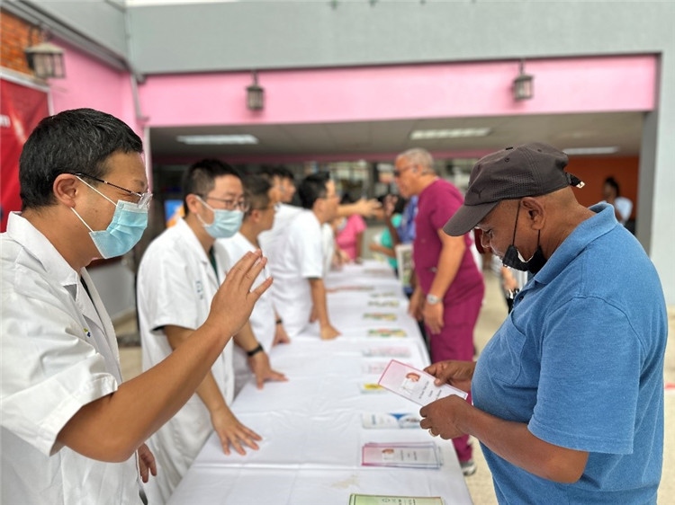 援圭醫(yī)療隊隊員們在啟動儀式上為當?shù)孛癖姺职l(fā)宣傳手冊。中國援助圭亞那醫(yī)療隊供圖