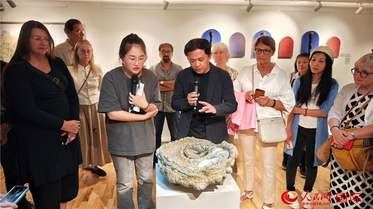 參展人、景德鎮(zhèn)陶瓷大學(xué)設(shè)計藝術(shù)學(xué)院副院長余劍峰（中）向來賓介紹參展作品。人民網(wǎng)記者 殷淼攝