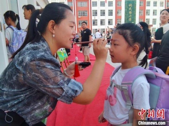 圖為衡水市利民路小學(xué)，老師為學(xué)生點(diǎn)朱砂痣，寓意開啟智慧。張松 攝