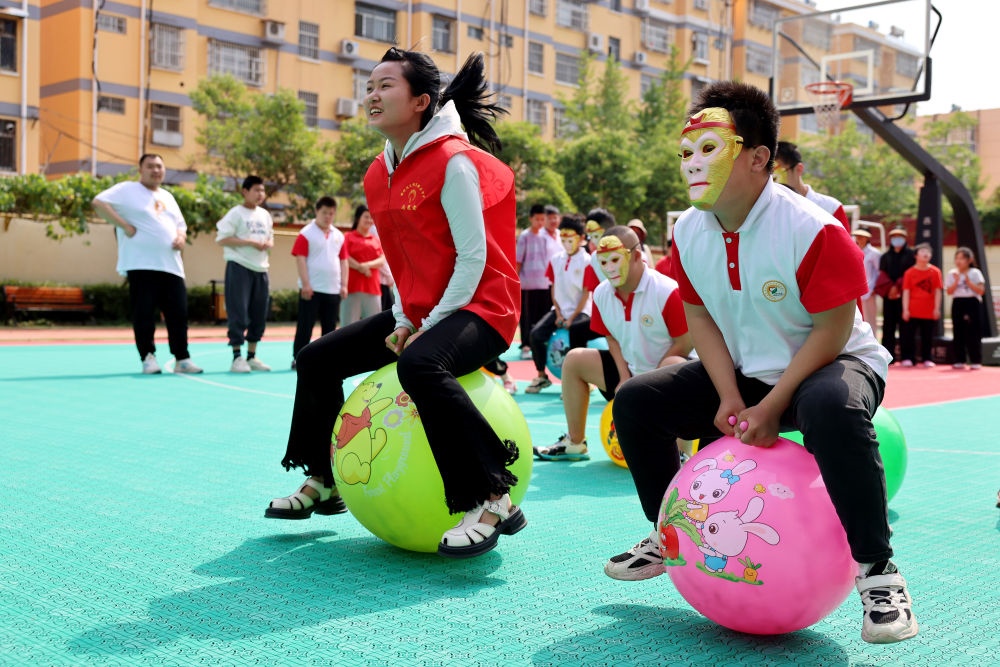 2024年5月17日，在山東省棗莊市市中區(qū)特殊教育中心，青年志愿者與智力障礙學(xué)生一起做游戲。新華社發(fā)（孫中喆攝）
