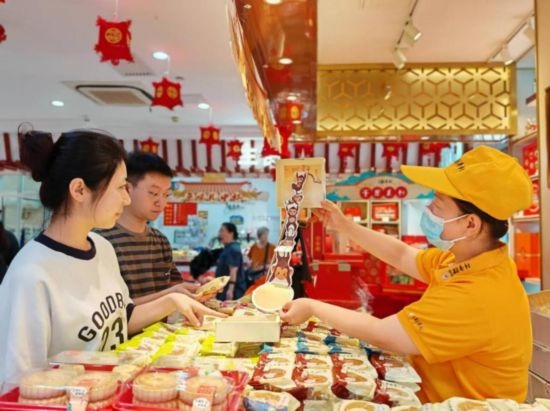 北京稻香村一家門店內(nèi)，售貨員向顧客展示新上市的月餅禮盒。（受訪者供圖）