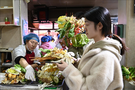 游客挑選好麻辣燙菜品后排隊等待加工。新華社記者 范培珅 攝