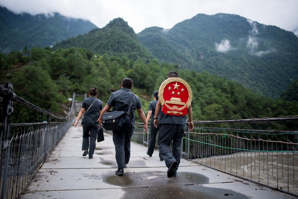 云南省怒江傈僳族自治州貢山縣人民法院法官鄧興背著國徽與同事們跨過怒江（2019年8月30日攝）。怒江高山峽谷眾多，交通不便，為方便群眾、更好地開展法律服務(wù)，背著國徽攀高山、過索橋、躲落石、鉆老林……成為鄧興法官的工作常態(tài)。新華社記者 江文耀 攝