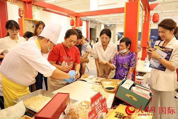 演出前，在天津桂發(fā)祥十八街麻花制作技藝非遺體驗展臺前，泰國民眾體驗天津麻花制作。人民網(wǎng)記者 楊一攝