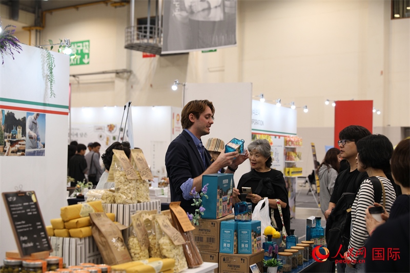 當(dāng)?shù)貢r(shí)間10月5日，在第21屆釜山國(guó)際美食博覽會(huì)上，意大利展商向參觀者們介紹的意大利食品。人民網(wǎng)記者 莽九晨攝