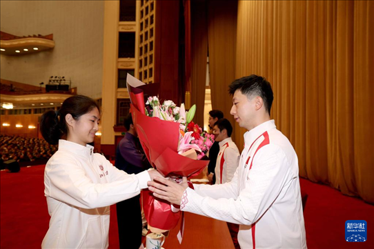 11月15日，一名學(xué)生代表在報(bào)告會(huì)上向乒乓球運(yùn)動(dòng)員馬龍（右）獻(xiàn)花。新華社記者 李明 攝