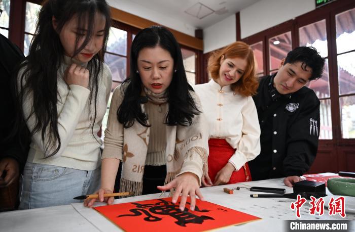 1月20日，西泠印社社員李硯（左二）為外籍留學生講述蛇年福字貼創(chuàng)作靈感。當日，來自巴西、馬來西亞、加納、哈薩克斯坦的外籍留學生在浙江杭州西泠印社體驗福貼、春聯(lián)和篆刻，感受古老的中國傳統(tǒng)文化。中新社記者 王剛 攝