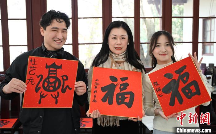 1月20日，外籍留學生和西泠印社社員李硯(中)展示各自創(chuàng)作的福貼。當日，來自巴西、馬來西亞、加納、哈薩克斯坦的外籍留學生在浙江杭州西泠印社體驗福貼、春聯(lián)和篆刻，感受古老的中國傳統(tǒng)文化。中新社記者 王剛 攝