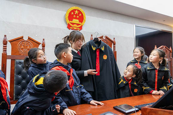 圖②：干警向同學(xué)們介紹法袍。