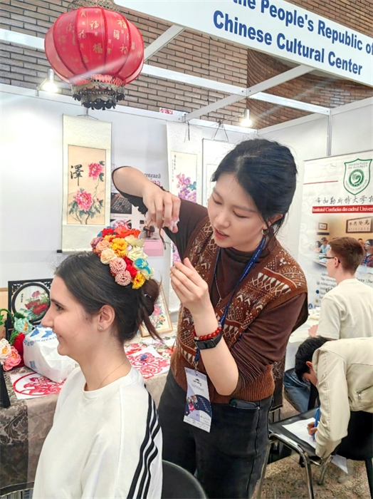 展覽正值羅馬尼亞迎春花節(jié)，國(guó)際中文教師志愿者潘婧穎向游客們介紹了國(guó)家非物質(zhì)文化遺產(chǎn)——福建泉州的簪花文化。布加勒斯特大學(xué)孔子學(xué)院供圖。